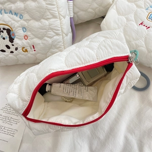Detail of white quilted heart cosmetic bag with cute dog embroidery and red zipper