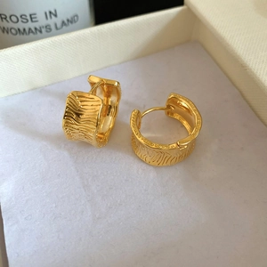 Close-up of 18K gold plated wide hoop earrings with textured wavy metal surface