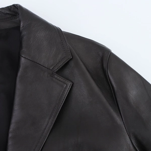 Close-up of the notched lapel and shoulder seams on a black PU leather jacket