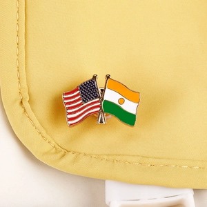 Macro shot of crossed USA and Niger flags enamel brooch pin on yellow fabric