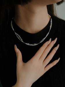 Close-up of multilayered beaded necklace with gold bar accents on a black sweater