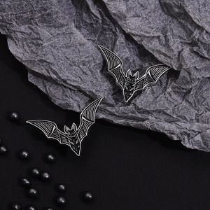 Gothic black bat alloy brooch with silver wings set against a textured dark background