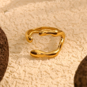Macro d'une bague ouverte dorée 18 carats au design irrégulier sur fond de pierre blanche