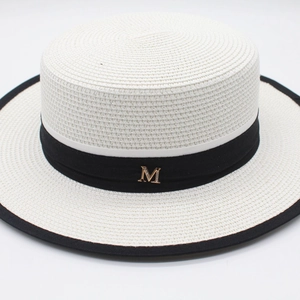 Detail of white woven boater hat with black ribbon and gold diamond-encrusted M buckle