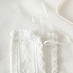 Detail of white Lolita socks featuring ribbon lace-up, heart knit patterns and ruffled edges