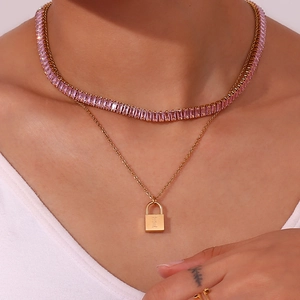 Close-up of layered 18K gold necklaces with pink zircon tennis chain and lock pendant