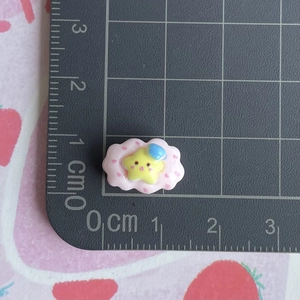 Detailed view of mini pink cloud resin charm with yellow star on a metric cutting mat