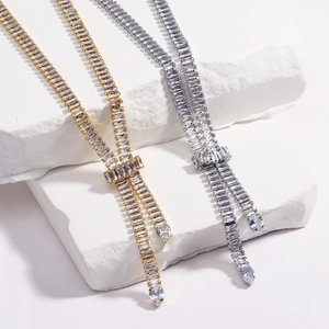 Dettaglio di collane con nappe in oro e argento con zirconi su sfondo di pietra