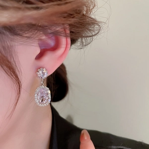 Close-up of elegant halo-set zircon flower pearl earrings worn on a model ear