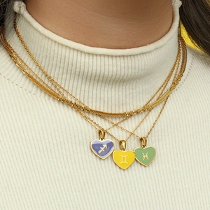 Golden layered necklace set featuring three colorful heart-shaped zodiac charms on a model