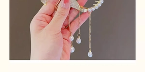 Détail de la pince à cheveux dorée avec pompons, strass et perles pour filles