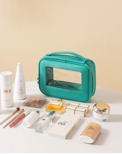 Dettaglio del beauty case verde menta in pelle con finestra trasparente e trucchi