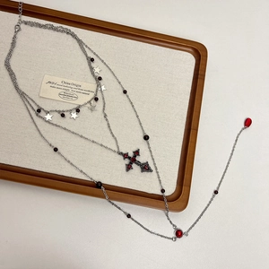 Detail of layered silver necklace with red crystal cross and star pendants on a display