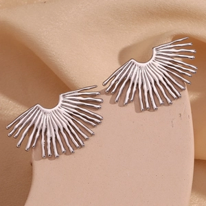 Detailed macro view of silver ray-shaped fan earrings with radial texture on silk