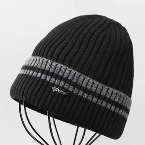 Detail of black ribbed knit beanie with grey stripes and silver metal sport emblem