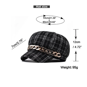 Detail of plaid newsboy hat featuring dimensions, tweed texture and gold chain detail