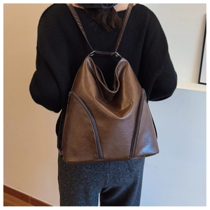 Detail view of the soft brown leather texture and stitching on a large vintage backpack