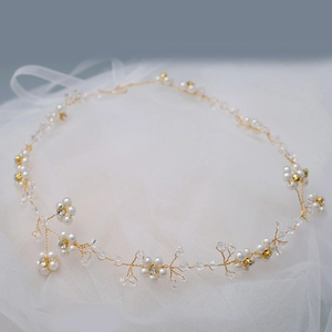 Detailed close-up of bridal headpiece featuring gold wire, white pearls, and crystals