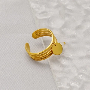 Detail view of gold layered wavy ring featuring a round pendant and white bead charm