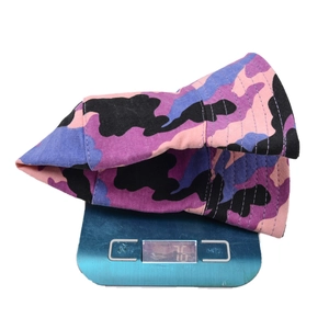 Detailed view of camouflage bucket hat on an electronic scale showing 76g product weight