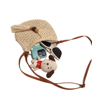 Beige woven straw crossbody bag with brown leather strap and decorative tassels