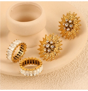Détail de bagues en strass doré et boucles d'oreilles soleil sur support en céramique