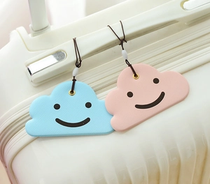 Close-up of cloud-shaped luggage tags in blue and pink colors on a suitcase handle