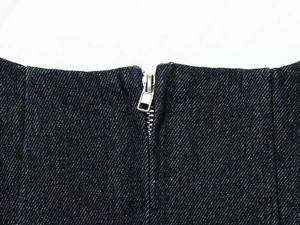 Detailed macro view of the silver metal zipper on a dark blue denim short dress fabric