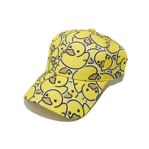 Detail of yellow baseball cap featuring cute all-over cartoon duck pattern and cotton texture