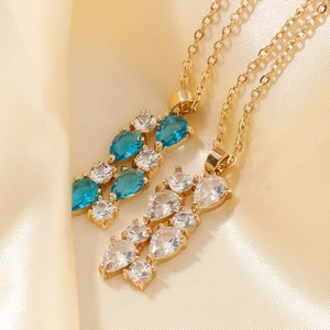 Macro shot of colorful pear-cut zircon pendants on gold chain necklaces with silk background