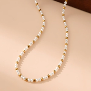 Detailed view of alternating white pearls and golden stainless steel beads on the necklace