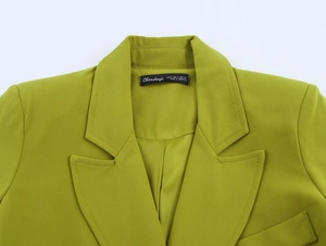 Detail of green blazer lapel showing twill fabric texture and interior brand label