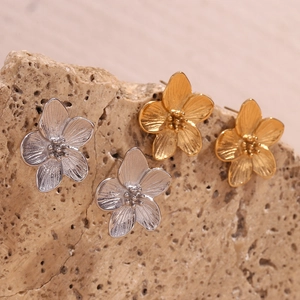 Macro shot of 3D flower stud earrings in gold and silver finish on natural stone