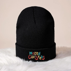 Black knit beanie with colorful Merry Christmas embroidery on a plush background