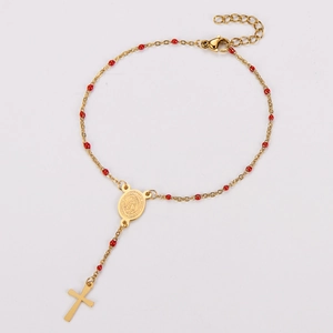 Close-up of golden stainless steel cross bracelet with red beads and Virgin Mary medal
