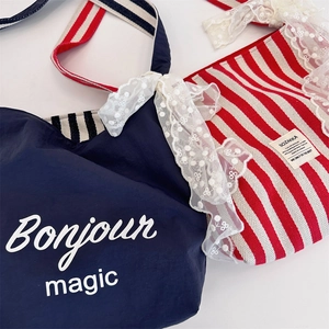 Detail of canvas tote bags featuring lace bow accents and striped shoulder straps