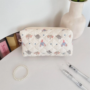 Detailed texture of white quilted pencil case featuring cartoon elephant pattern and zipper