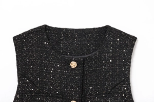 Detail of black tweed vest featuring golden sequins and embossed decorative buttons
