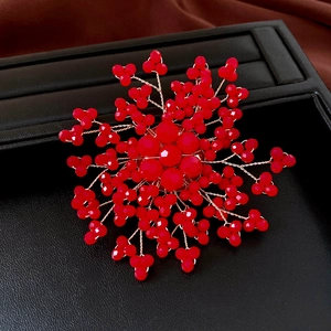 Dettaglio macro della spilla a fiore in cristallo rosso fatta a mano con filo dorato
