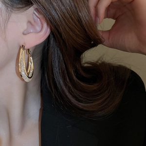 Close-up of gold double-layer U-shaped earrings with sparkling inner texture on model