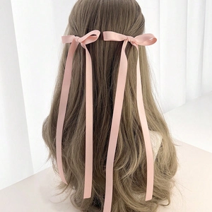 Detail of pink satin ribbon bow hair clips with long streamers on a model's hair