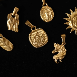 Detailed view of assorted gold plated titanium steel charms on black velvet background