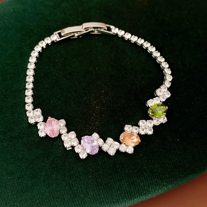 Detailed shot of zircon bracelet with colorful oval gems on green velvet stand