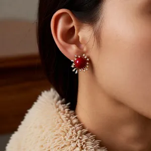 Elegante rote runde Ohrstecker mit Zirkon-Halo und Goldfassung am weiblichen Model