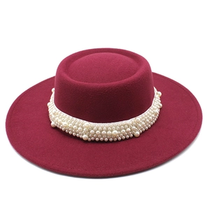 Detail of burgundy wool boater hat featuring elegant multi-row white pearl decorative band