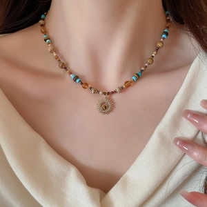 Detail of beaded necklace with sun pendant and natural tiger eye stone on a model