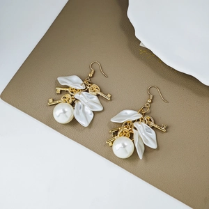 Detail of vintage French gold earrings with white petals, pearls, and golden key charms