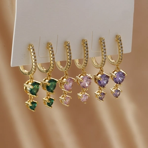 Three pairs of gold plated hoop earrings with colorful round cut zircon stones on silk