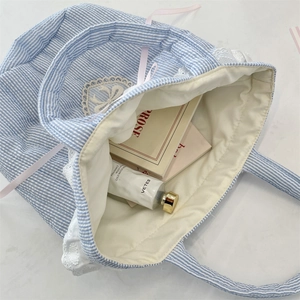 Dettaglio borsa a secchiello a righe blu con pizzo, ricamo a cuore e nastri rosa