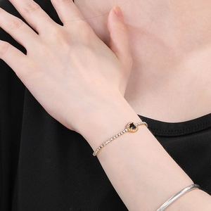 Close-up of golden heart bracelet featuring a black gemstone and white zircons on wrist